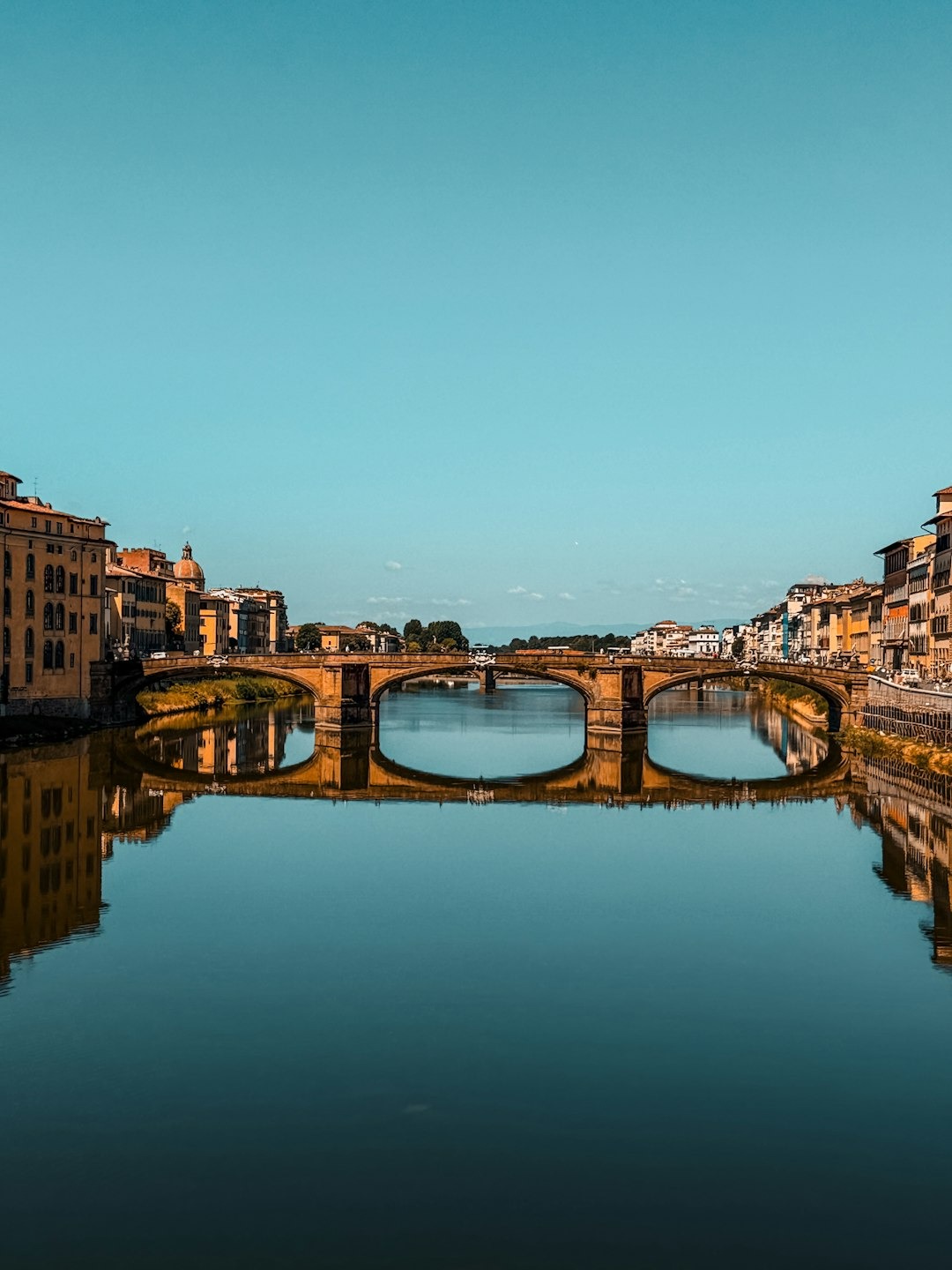 Historic bridge reflected in calm water under clear sky